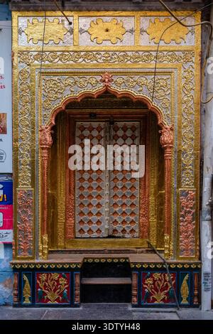 Ornate golden and silver doorway of a traditional building in Old Delhi, featuring intricate floral carvings and decorative patterns. Stock Photo