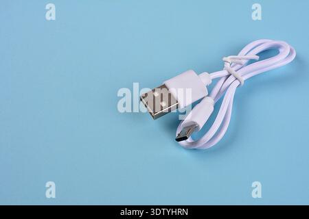 Close-up of a White USB Cable.A white USB type C charger cable, compatible for many devices, wrapped in a spiral shape, isolated. Stock Photo