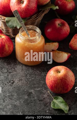 Apple jam and red fresh apples on a black stone table. Stock Photo