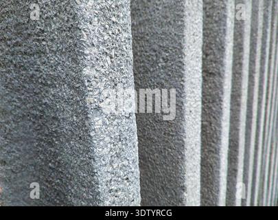 A high-contrast vertical shot of grey concrete slats in Újpest. This brutalist architectural detail features a rough stone-wash finish, ideal for mode Stock Photo