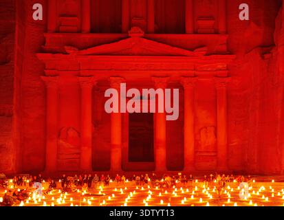 Visitors enjoy a candlelight event in front of Al Khazneh, the Treasury, in Petra, Jordan, creating a warm glow in the ancient site. Stock Photo
