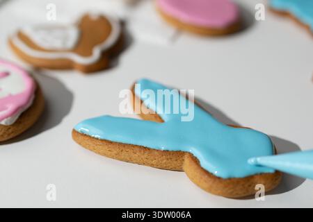 People are baking gingerbread cookies shaped like Easter symbols. The cookies are decorated with colorful icing. This activity takes place during the Easter celebration. Stock Photo