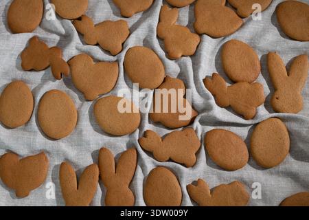 Gingerbread cookies are laid out on a cloth. The cookies are shaped like bunnies, eggs, and chicks. They represent Easter traditions and the spirit of the celebration. Stock Photo