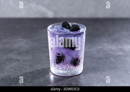 Bramble cocktail with blackberries and crushed Ice on gray stone background Stock Photo
