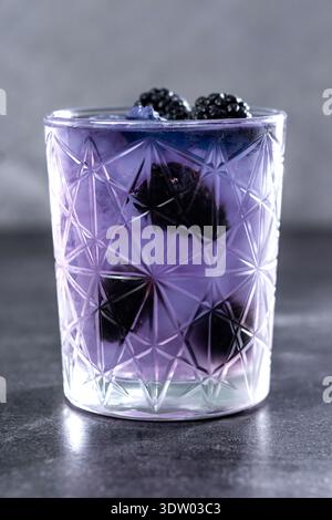 Bramble cocktail with blackberries and crushed Ice on gray stone background Stock Photo