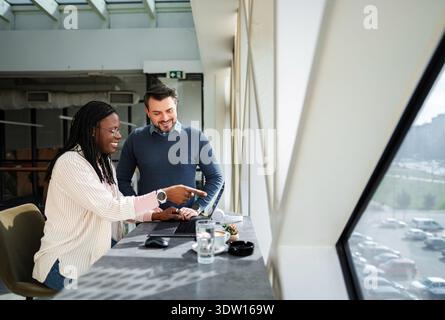 Diverse business professionals collaborating on laptop in modern office Stock Photo