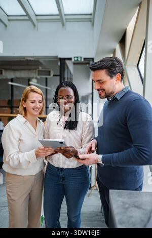 Diverse business professionals collaborating smiling using digital tablet Stock Photo