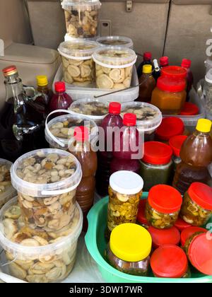 Variety of homemade preserves, honey, herbal infusions and dried fruits in plastic jars and bottles. Natural products at local market. Stock Photo
