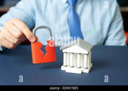 A bank and a broken security lock. Security breach and threat of hacking. Banking system vulnerabilities and cyberattack risk management Stock Photo