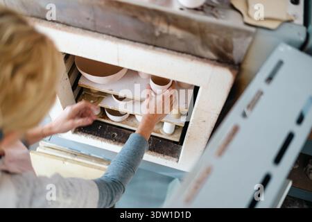 Close-up of ceramic artist keeping her ceramic plates and bowls in the kiln Stock Photo