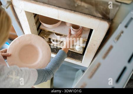 Close-up of ceramic artist keeping her ceramic plates and bowls in the kiln Stock Photo