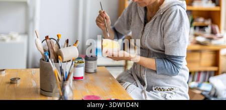 Unrecognisable Female Potter Decorating A Clay Pot In Her Workshop Stock Photo