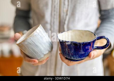Woman's hands holding two handmade cups, close-up Stock Photo