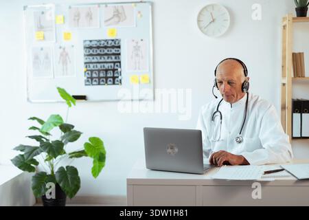 Senior male doctor consulting patient during an online consultation on laptop. virtual medical support. General practitioner or medical worker on tele Stock Photo