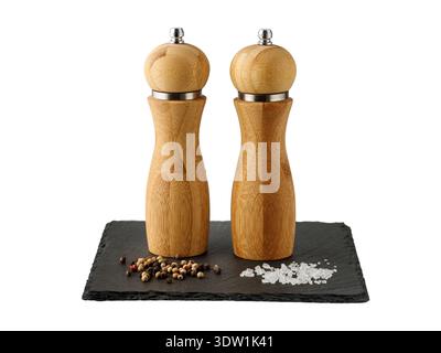 Wooden salt and peppers mill on black slate board isolated on white background. Two bamboo spice grinders. Stock Photo