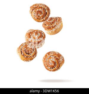 Fresh baked cinnamon buns flying falling isolated on white background. Traditional swedish sweet pastry kanelbulle. Stock Photo