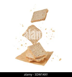 Cutting slices of whole grain wheat bread with crumbs flying, falling on paper sheet isolated on white background. Toast bread pieces. Healthy food co Stock Photo