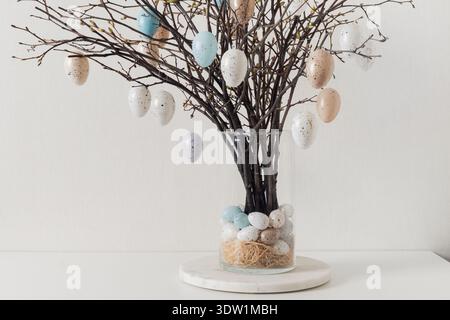 Easter tree decorated white and beige eggs in vase on white table. Stock Photo