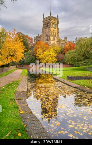 View of a church and reflection in a canal in autumn time with golden leaves on trees and water. Stock Photo