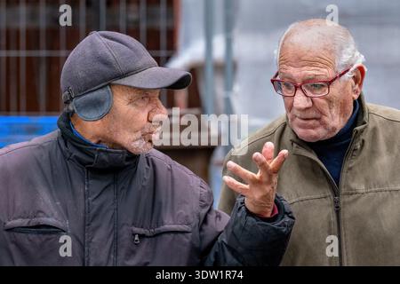 Two older men in conversation in a fish market at Piazza Alonzo di Benedetto, Catania, Sicily, Italy. Stock Photo