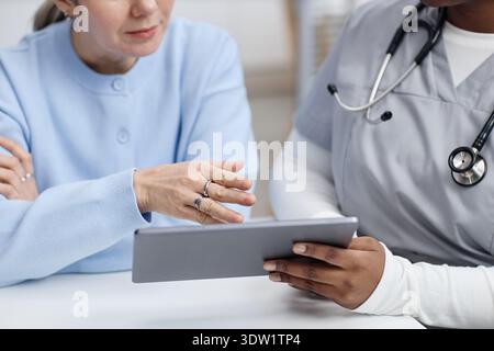 Middle Aged Caucasian Woman Discussing Medical Information with Black Nurse Stock Photo