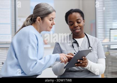Middle Aged Caucasian Woman Discussing Medical Results with Black Female Nurse Stock Photo