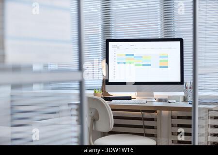 Modern Office Desk Featuring Computer Monitor Displaying Digital Calendar Stock Photo