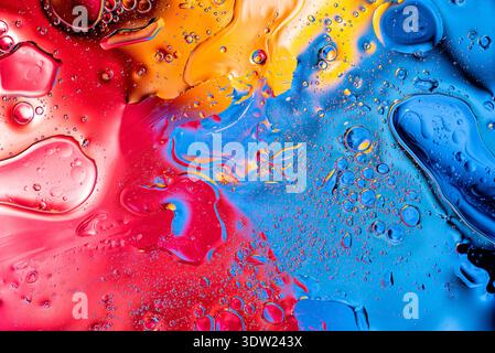 Dynamic mixture of yellow red and blue liquids forming organic bubble shapes and swirling patterns for contemporary wallpaper and digital art Stock Photo