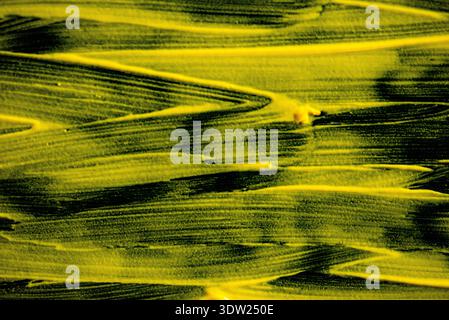 Modern artistic texture featuring vibrant yellow acrylic brush strokes on dark surface for creative graphic design and contemporary backgrounds Stock Photo