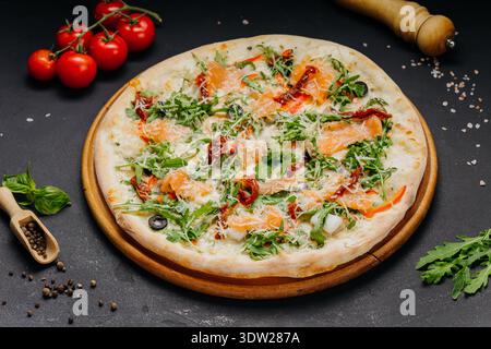 Gourmet pizza with salmon arugula cheese and sun dried tomatoes on wooden board Stock Photo