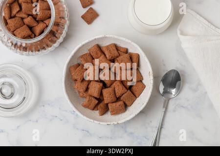 Chocolate pads in a white plate on a marble table and a glass of milk. A delicious and healthy breakfast. Selective focus, top view Stock Photo