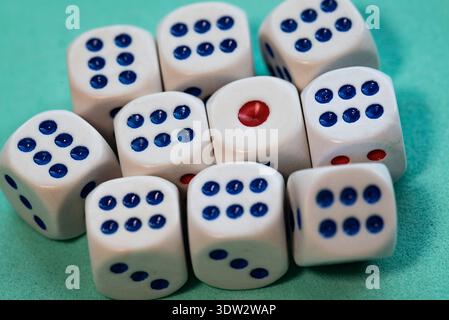 Close-up of a group of white dice with blue dots and a single red dot, arranged on a green surface. The composition emphasizes randomness and probabil Stock Photo