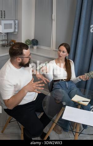 Young man and woman sitting at a table having a serious money argument, debating their budget, expenses, income, debt, and future financial planning i Stock Photo