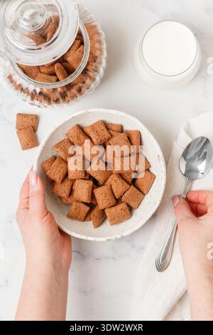 Chocolate pads in a white plate on a marble table and a glass of milk. A delicious and healthy breakfast. Selective focus, top view Stock Photo