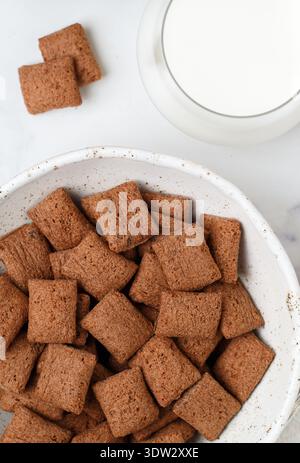 Chocolate pads in a white plate on a marble table and a glass of milk. A delicious and healthy breakfast. Selective focus, top view Stock Photo