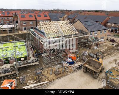 Aerial view above a construction site building new and affordable eco friendly houses with solar panels in the UK with exposed roof rafters and scaffo Stock Photo