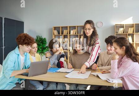 High school students and teacher collaborating on project in classroom library Stock Photo