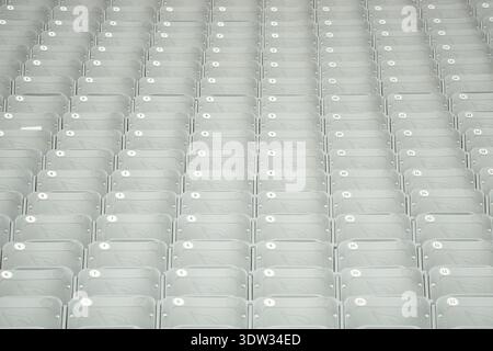 Rows of seats, each with a white numbered label, are tightly arranged in a grid pattern. The seats are part of a large, organized seating area Stock Photo