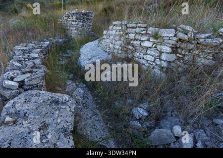 A dramatic travel image focusing on the historic City Wall of Erice, showcasing the massive, irregularly shaped cyclopean stones (polygonal masonry) t Stock Photo