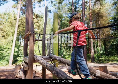 Child balancing on playground equipment in summer forest park Stock Photo