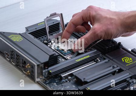 Sarajevo, Bosnia and Herzegovina – February 13, 2026: Hand installing AMD ryzen processor into AM5 motherboard socket during desktop computer assembly Stock Photo