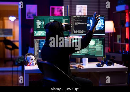 Hacker wearing VR headset uses AI machine learning to develop zero day exploit undetectable by antivirus. Rogue engineer uses virtual reality and neural networks to build script doing data mining Stock Photo