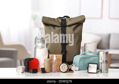 Emergency backpack and necessities on table at home Stock Photo