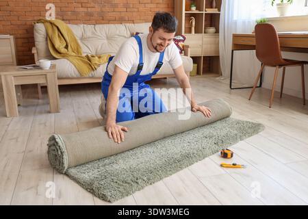 Male loader rolling out carpet in room Stock Photo