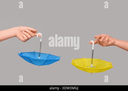 Female hands with different mini umbrellas on grey background Stock Photo