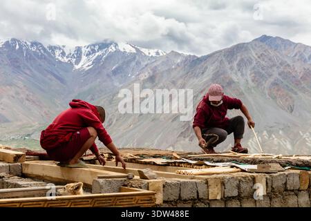 Two workers engage in construction against a backdrop of majestic mountains. Stock Photo