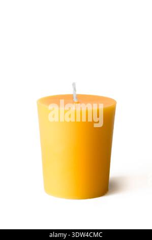 Flat top votive candle that is yellow and made of beeswax on white background Stock Photo