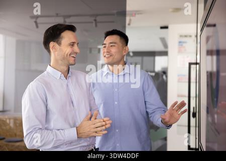 Two happy businessmen colleagues discussing project near wide digital display Stock Photo