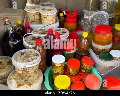 Variety of homemade preserves, honey, herbal infusions and dried fruits in plastic jars and bottles. Natural products at local market. Stock Photo