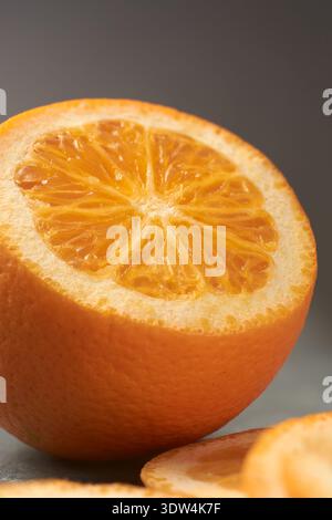 close-up of fresh halved raw orange on dark grey surface, juicy pulp and textured rind of citrus fruit, healthy nutrition concept, soft focus Stock Photo